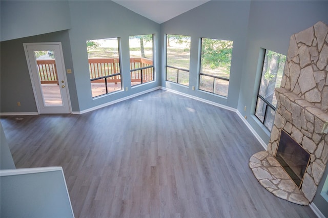 unfurnished living room featuring plenty of natural light, wood-type flooring, lofted ceiling, and a fireplace