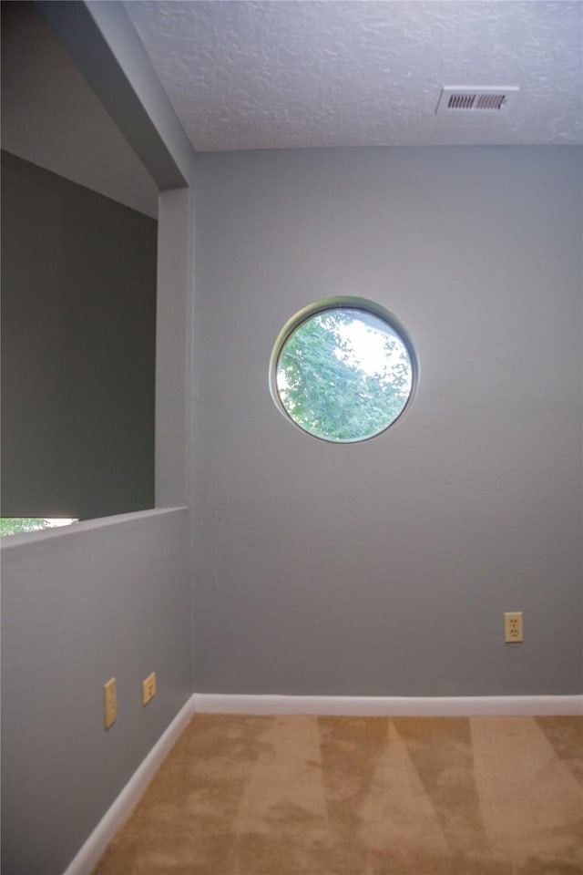 unfurnished room featuring a textured ceiling and carpet flooring