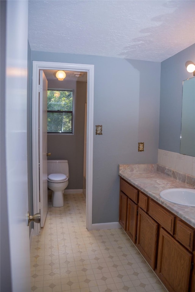 bathroom featuring a textured ceiling, toilet, and vanity