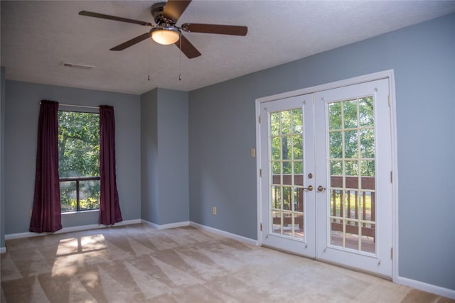 carpeted spare room featuring ceiling fan, french doors, a wealth of natural light, and a textured ceiling