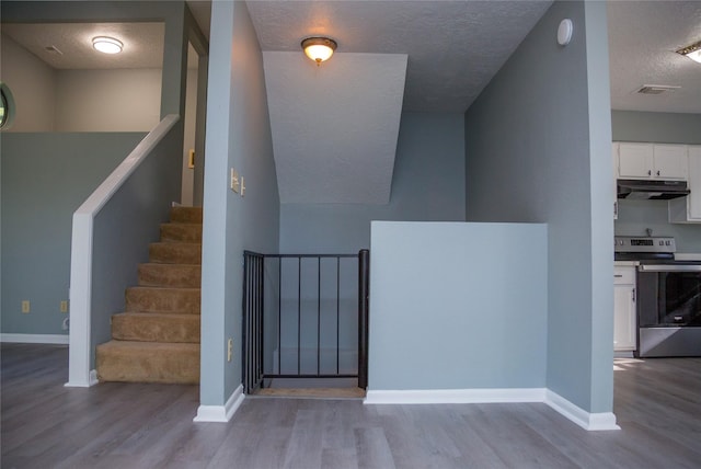 stairway featuring a textured ceiling and hardwood / wood-style floors