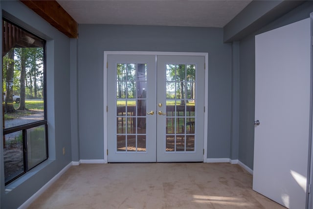 entryway with beam ceiling, light colored carpet, and french doors