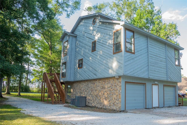 view of side of property featuring a garage, a wooden deck, and cooling unit