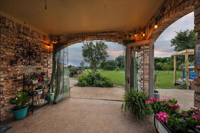 patio terrace at dusk featuring a yard