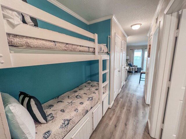 bedroom featuring light wood-type flooring, ornamental molding, and a textured ceiling