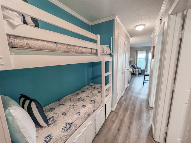 bedroom with ornamental molding, a textured ceiling, and light hardwood / wood-style floors