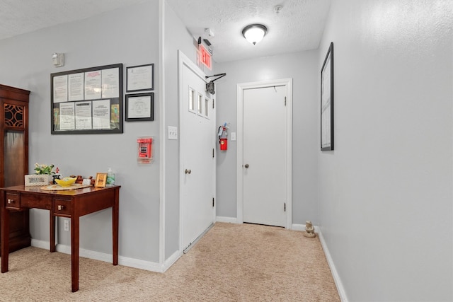 corridor with light colored carpet and a textured ceiling