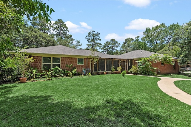 rear view of property featuring a yard and a sunroom