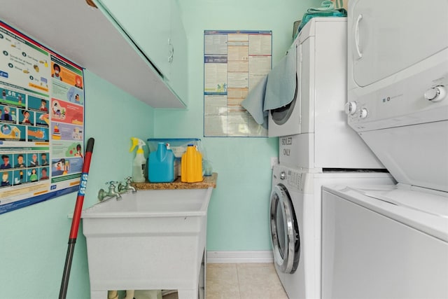 laundry area with light tile patterned floors, sink, cabinets, and stacked washer and clothes dryer