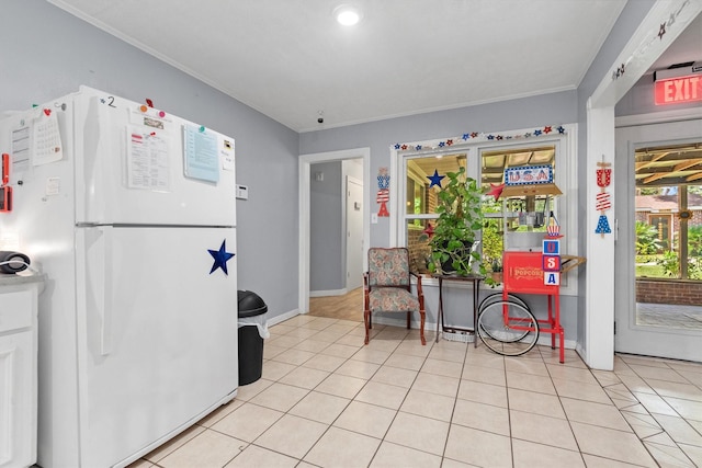 kitchen featuring white refrigerator, crown molding, and light tile patterned floors