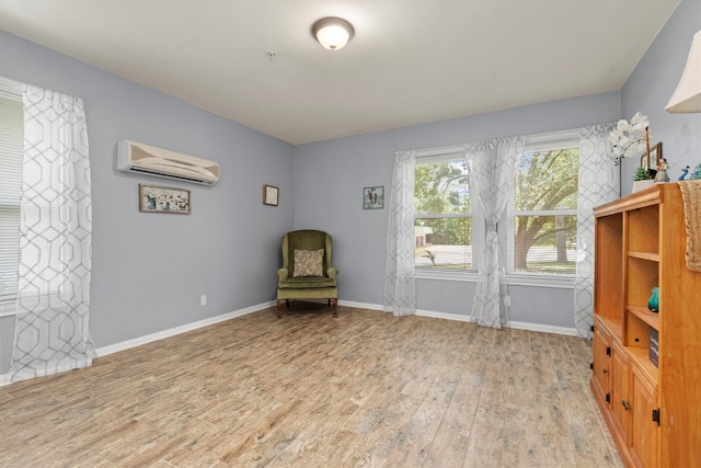 sitting room featuring an AC wall unit and light wood-type flooring