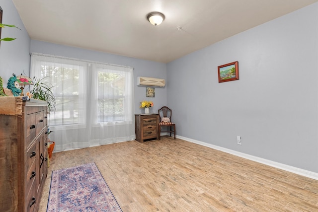 sitting room with a wall unit AC and light hardwood / wood-style flooring