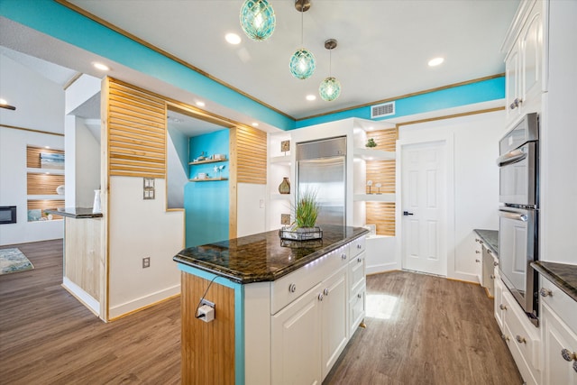 kitchen featuring appliances with stainless steel finishes, a center island, pendant lighting, and white cabinets