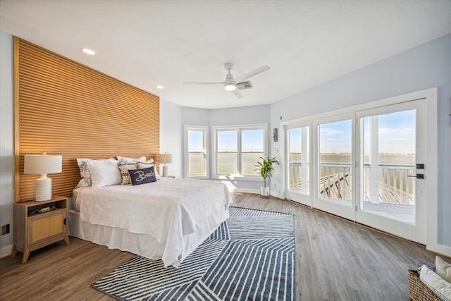 bedroom with a water view, ceiling fan, dark hardwood / wood-style floors, and access to exterior