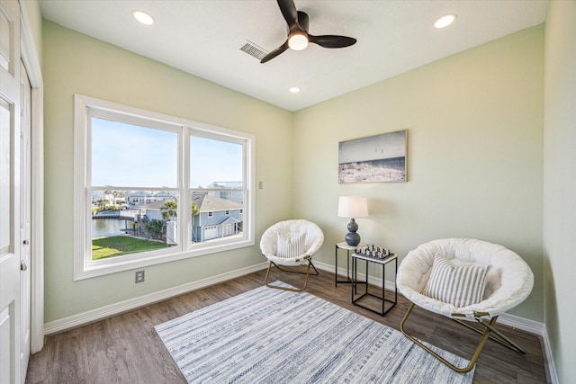 sitting room featuring light hardwood / wood-style floors, a water view, and ceiling fan