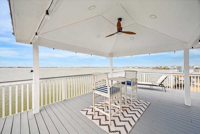 wooden terrace with a water view and ceiling fan