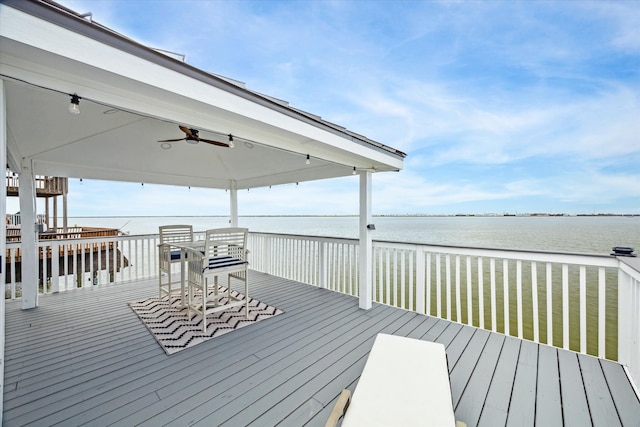 wooden terrace with a water view and ceiling fan