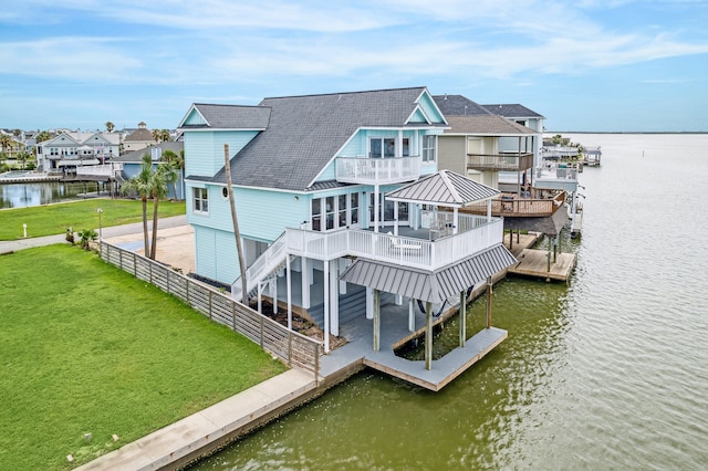 rear view of house featuring a lawn, a deck with water view, a gazebo, and a balcony