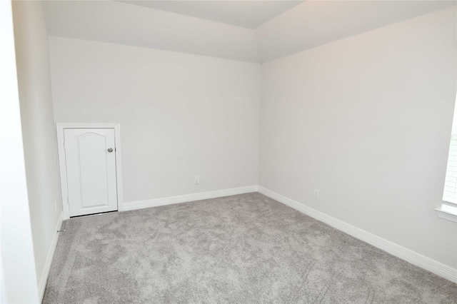 carpeted empty room featuring lofted ceiling