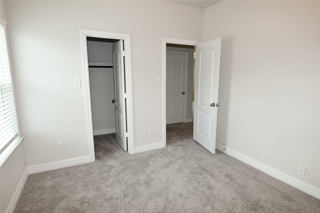 unfurnished bedroom featuring light carpet, a spacious closet, and a closet