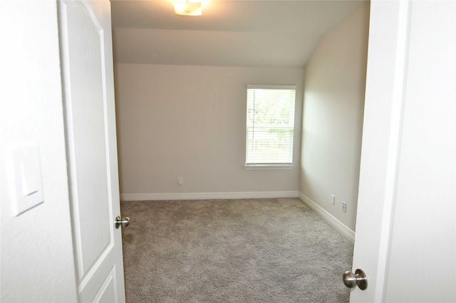 spare room featuring lofted ceiling and light carpet