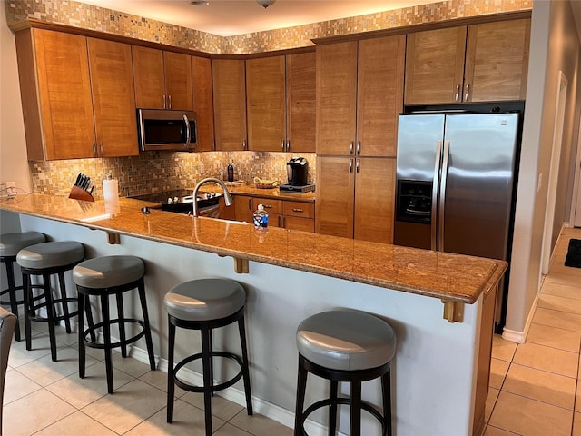 301 E Houston St Unit 3301, Port Isabel, TX 78578 - kitchen featuring appliances with stainless steel finishes, light tile patterned floors, a peninsula, and brown cabinets