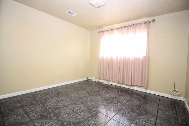 spare room featuring dark tile patterned flooring