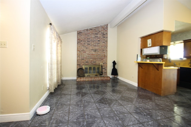 kitchen featuring dark tile patterned floors, vaulted ceiling, a brick fireplace, and brick wall