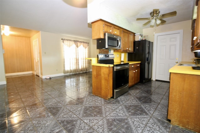 kitchen with sink, appliances with stainless steel finishes, ceiling fan, and dark tile patterned flooring