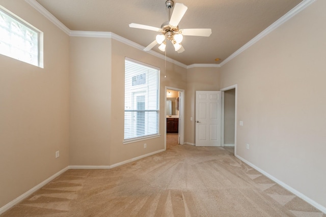 empty room with a healthy amount of sunlight, light colored carpet, and crown molding