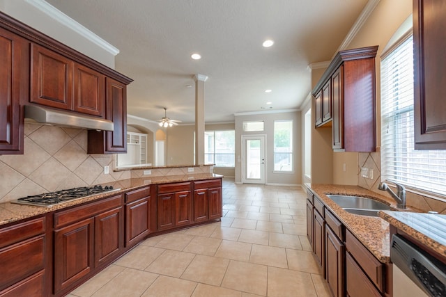 kitchen featuring light stone counters, under cabinet range hood, a sink, appliances with stainless steel finishes, and crown molding