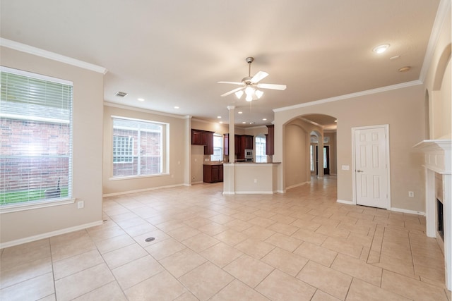 unfurnished living room featuring arched walkways, crown molding, a fireplace, light tile patterned flooring, and ceiling fan