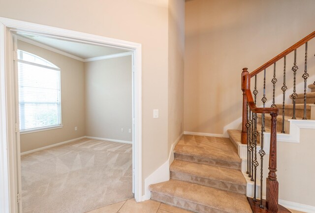 stairway with baseboards, carpet floors, ornamental molding, and tile patterned floors