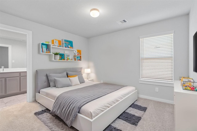 bedroom featuring ensuite bathroom and light carpet