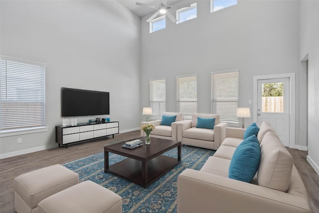 living room featuring dark hardwood / wood-style floors, ceiling fan, and a high ceiling