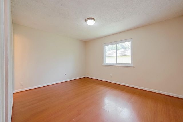 spare room with a textured ceiling and hardwood / wood-style floors