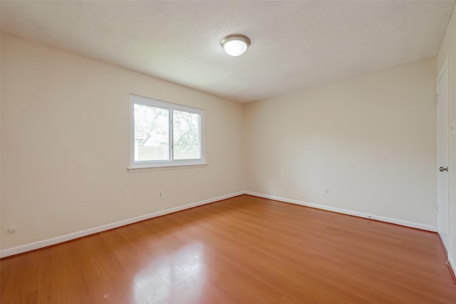 unfurnished room with a textured ceiling and hardwood / wood-style floors