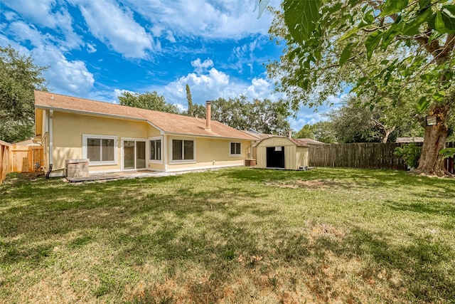 back of house featuring a yard, a patio, and a storage unit