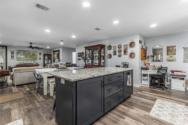 kitchen featuring light stone countertops, dark wood-type flooring, ceiling fan, and a kitchen island