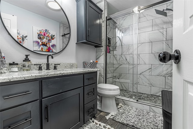 bathroom featuring toilet, vanity, and tiled shower