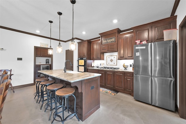 kitchen featuring a center island with sink, crown molding, hanging light fixtures, a kitchen breakfast bar, and stainless steel appliances