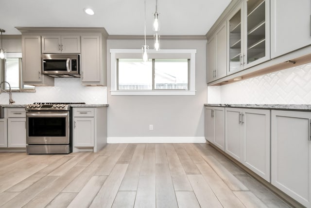 kitchen featuring stainless steel appliances, decorative light fixtures, light stone countertops, and gray cabinetry