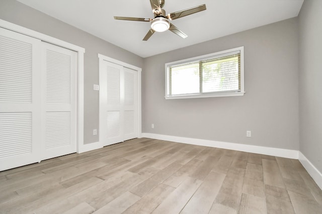 unfurnished bedroom featuring two closets, ceiling fan, and light wood-type flooring