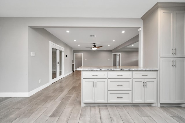 kitchen featuring white cabinetry, ceiling fan, and light stone counters