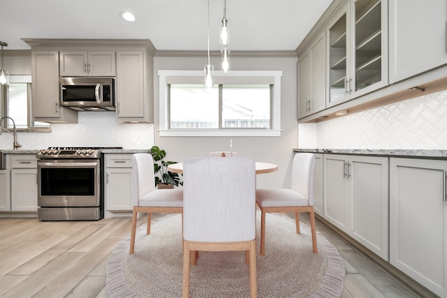 kitchen featuring pendant lighting, tasteful backsplash, stainless steel appliances, and light stone counters