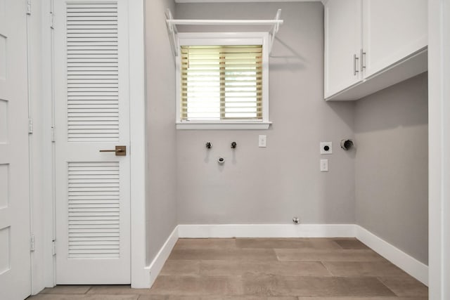 clothes washing area with cabinets, washer hookup, light hardwood / wood-style flooring, and electric dryer hookup