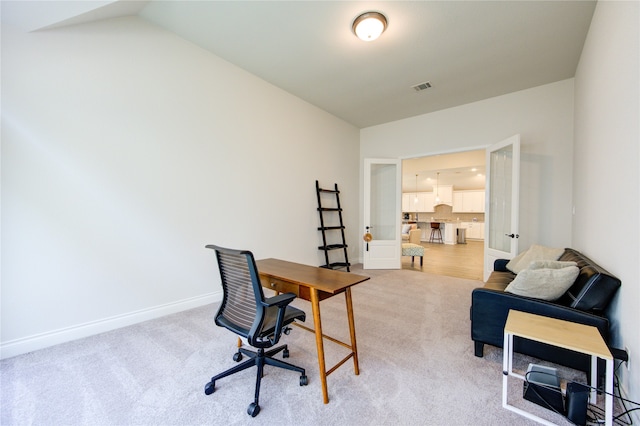 home office with vaulted ceiling and light carpet