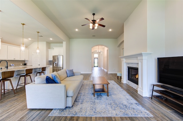 living room featuring ceiling fan, sink, hardwood / wood-style flooring, and a premium fireplace