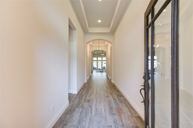 corridor with wood-type flooring and a tray ceiling