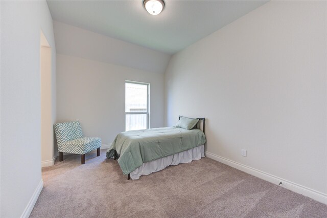 bedroom featuring light colored carpet and vaulted ceiling